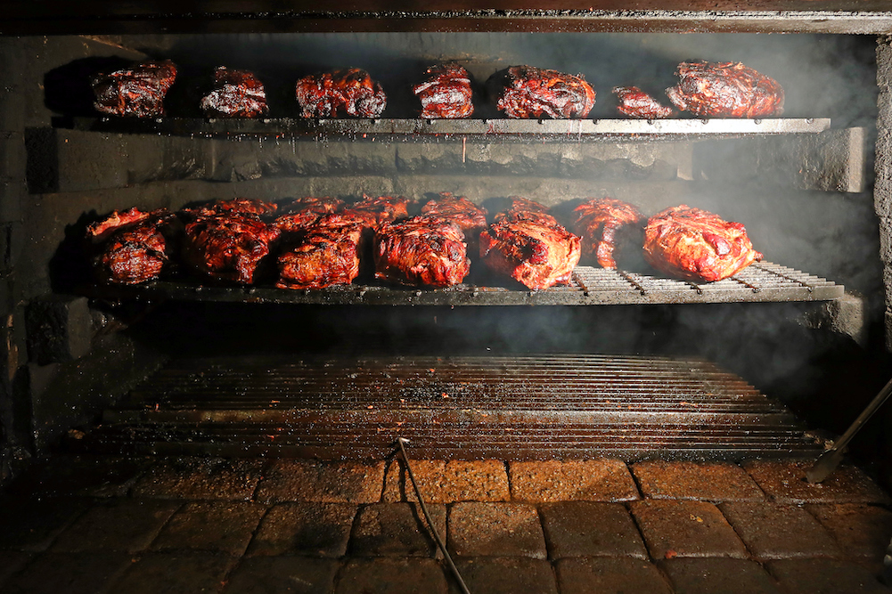 Pork being barbequed in a southern style pit over hickory wood.